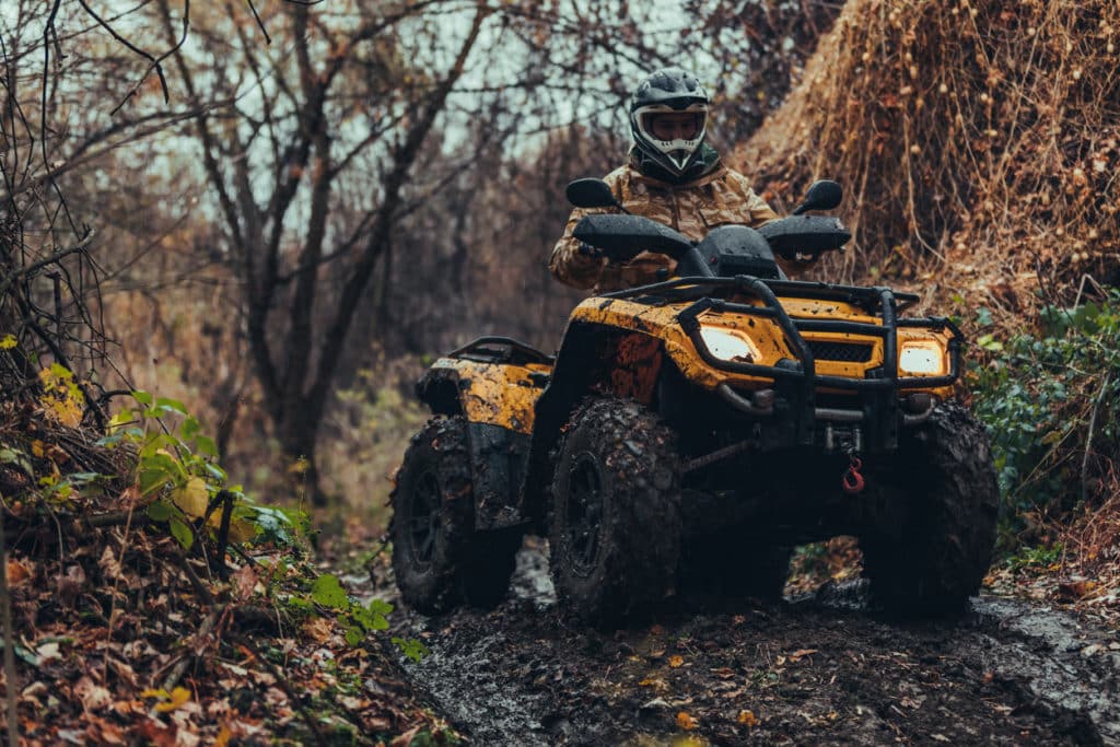 ATV Care - Unrecognizable person driving fix quad on a moody path through the forest