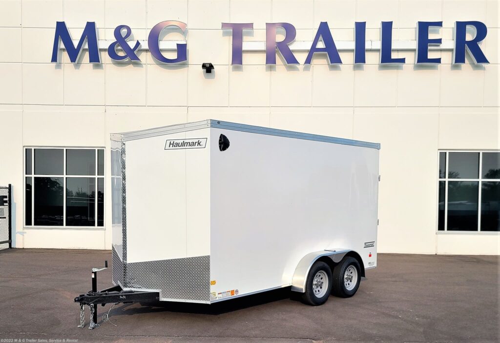 A white enclosed trailer by Haulmark, one of our trailer brands, parked by our building