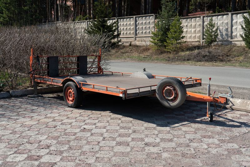 An orange utility trailer, one of the potential options when you buy a utility trailer, parked in an urban area.