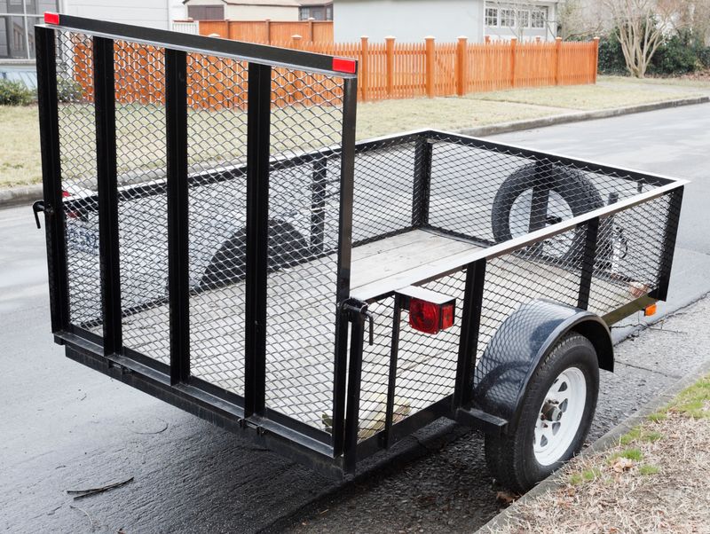 An open utility trailer parked in a residential neighborhood